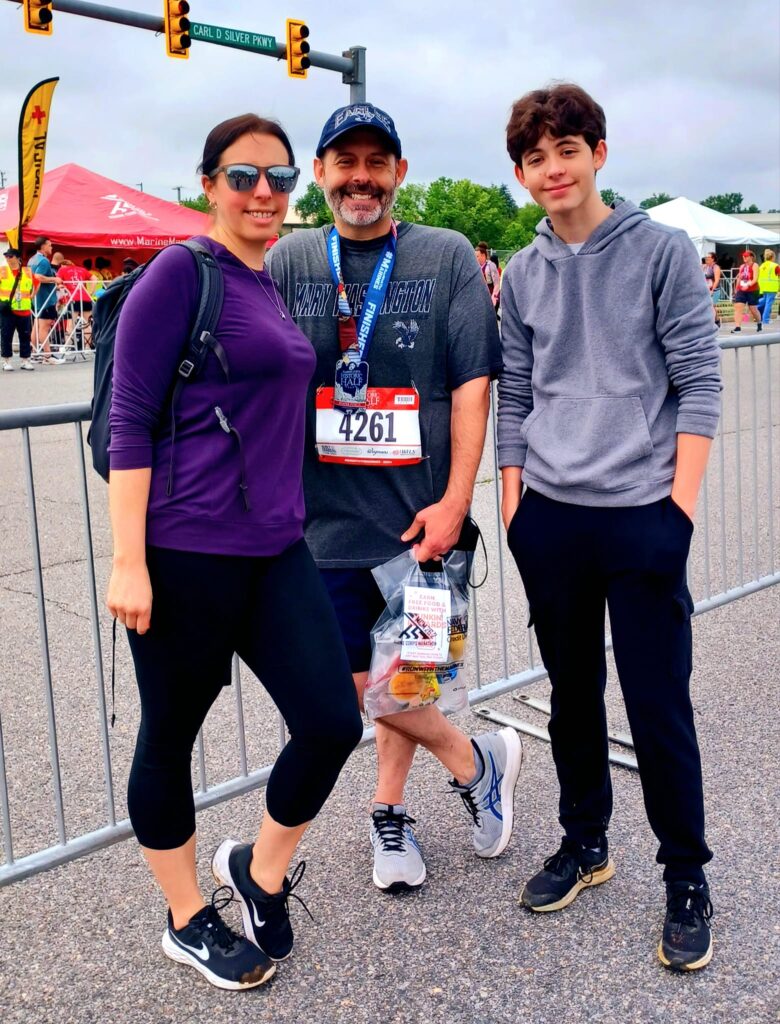 Three individuals photographed on the street after a half marathon.