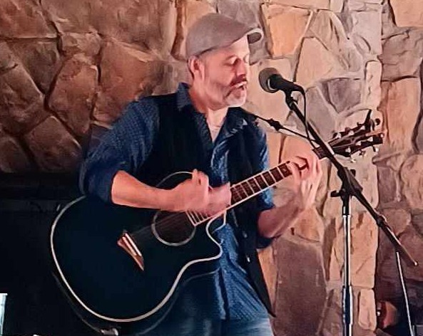 picture of Kevin playing a guitar and singing